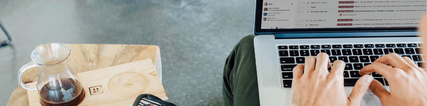 Hands on a keyboard with a list of emails on the laptop screen
